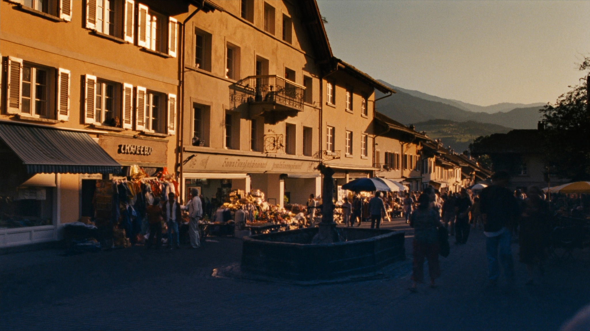 Belebte Schweizer Marktgasse mit lokalen Geschäften und Brunnen zur goldenen Stunde